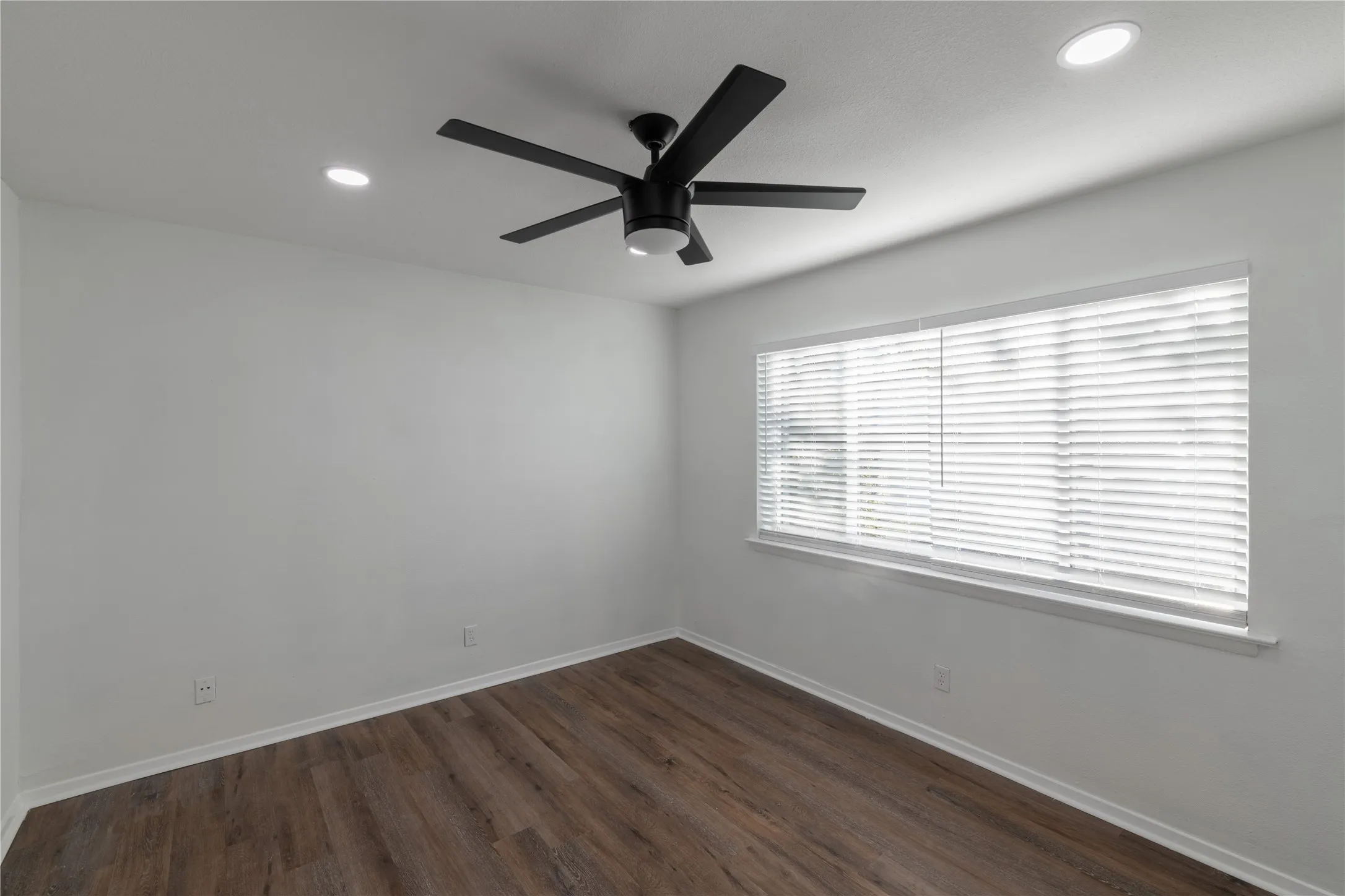 Room featuring a contemporary ceiling fan with integrated lighting, recessed ceiling lights, wood-finish flooring, and a window with horizontal blinds