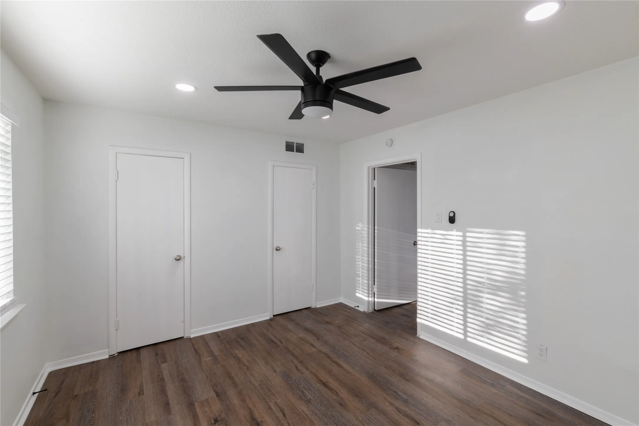 Spacious room featuring wood-finish flooring, recessed lighting, and a modern ceiling fan