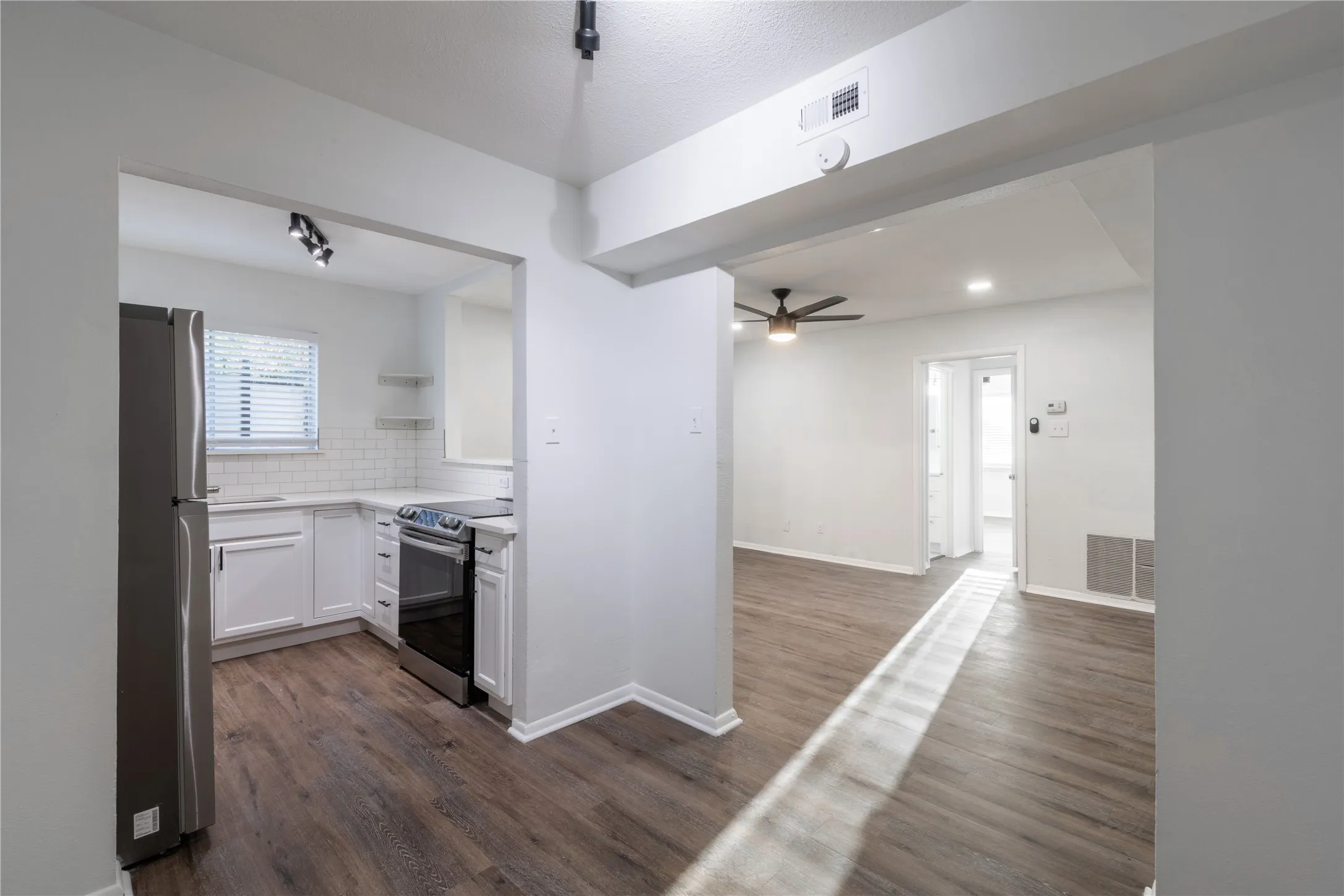 Kitchen featuring white cabinetry, subway tile backsplash, stainless steel appliances, and wood-finish flooring