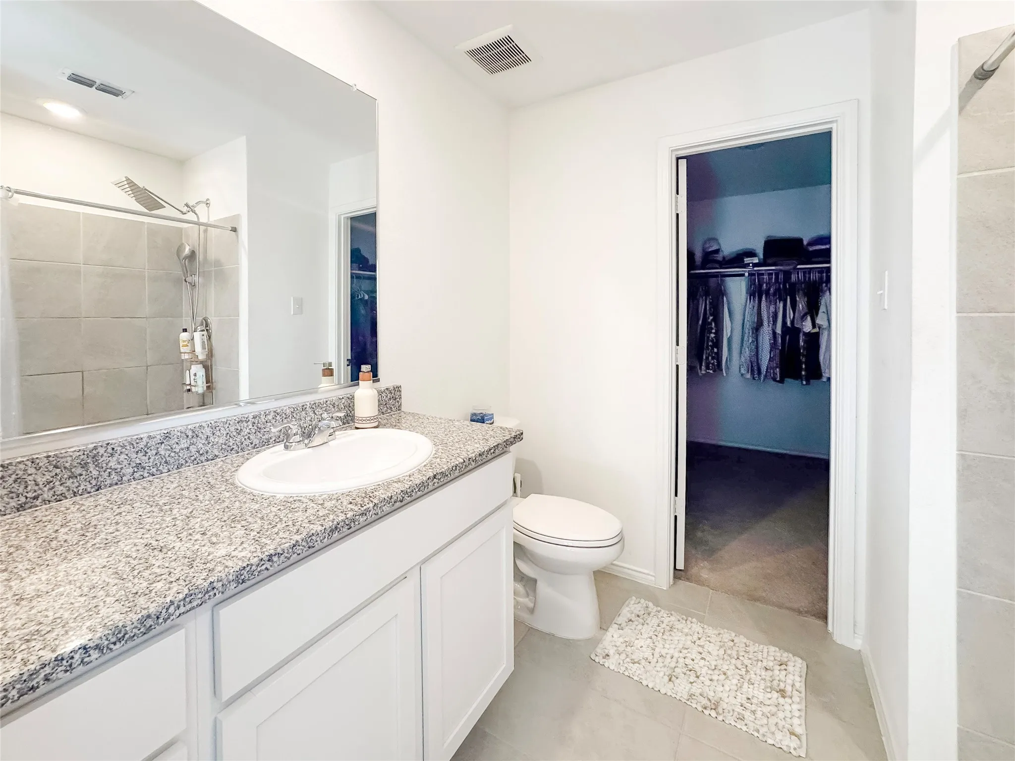 Bathroom featuring a white vanity with a granite-style countertop, an undermount sink, and a large wall-mounted mirror