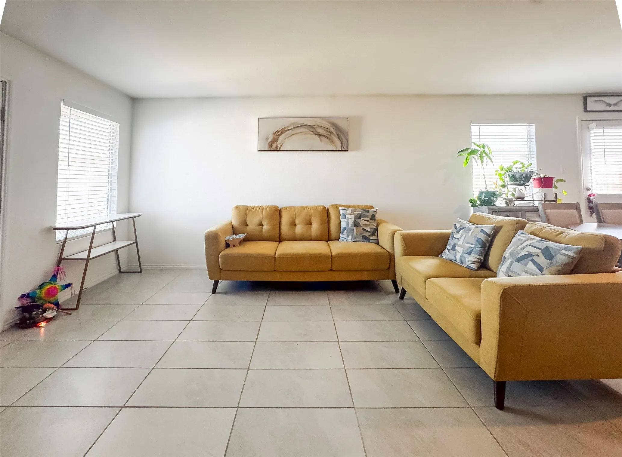 Spacious interior featuring light-toned tile flooring, white walls, and multiple windows with horizontal blinds