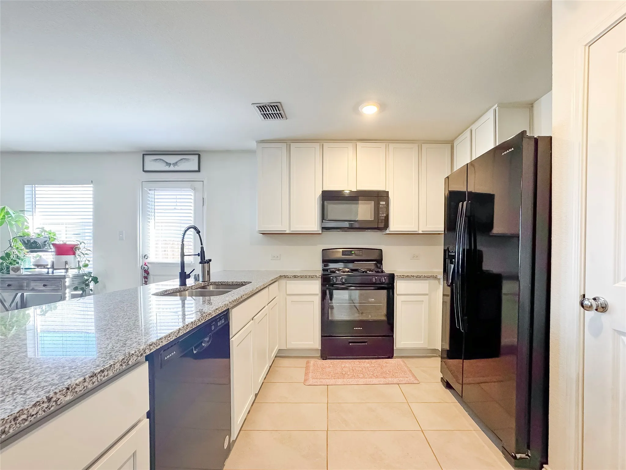 Kitchen featuring a large island with a double basin sink and gooseneck faucet