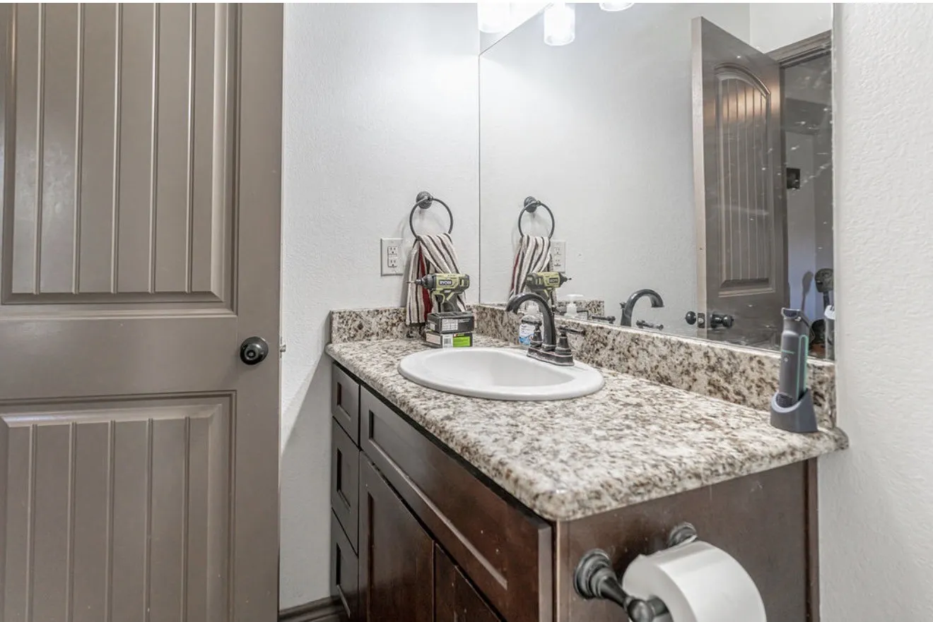 Bathroom vanity featuring a speckled countertop, undermount sink, and dark wood-finish cabinetry