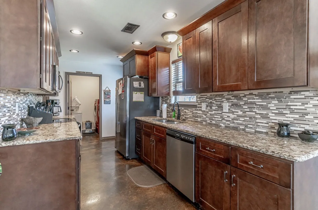 Kitchen featuring wood cabinetry, granite countertops, a mosaic tile backsplash, stainless steel appliances, and recessed lighting