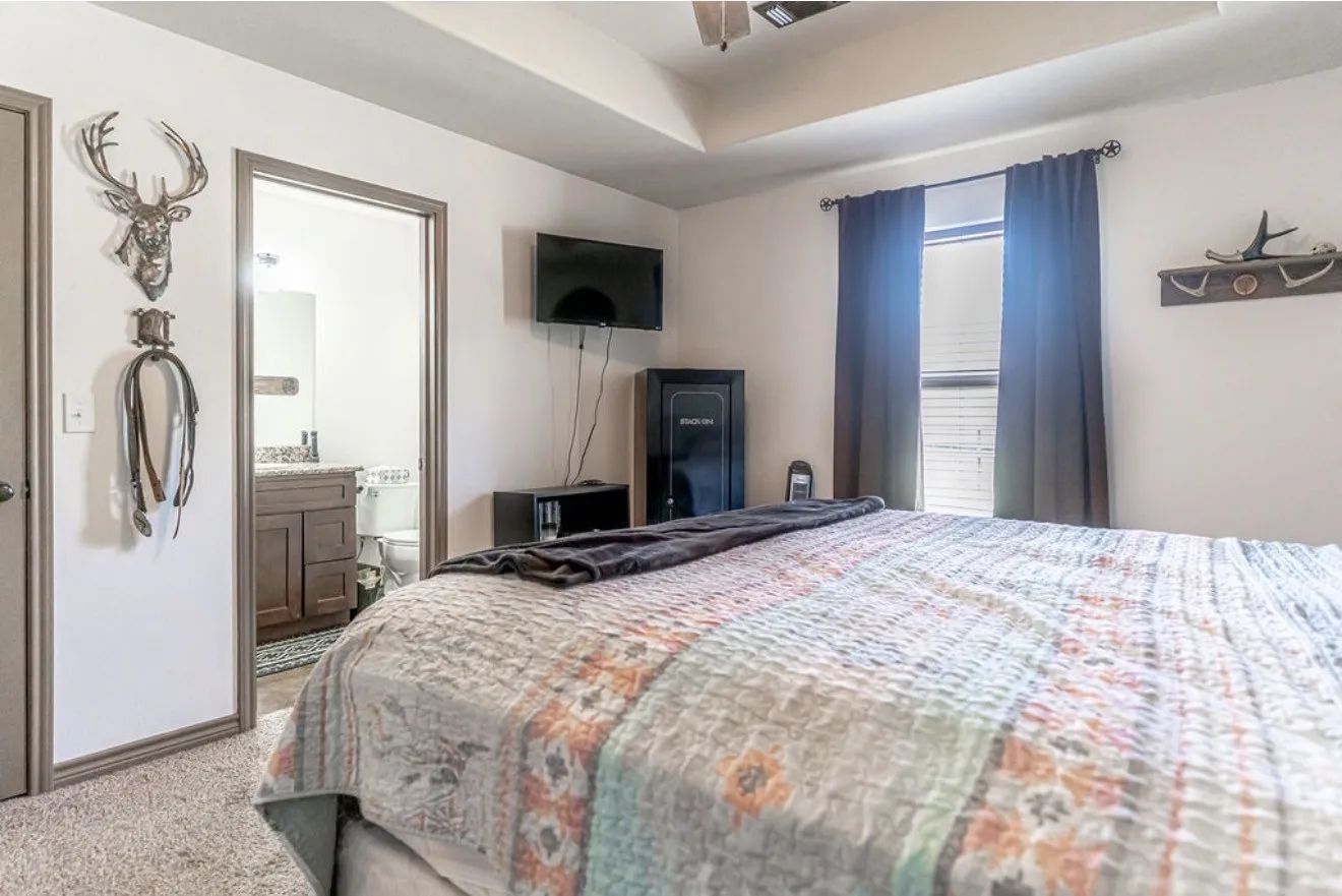 Carpeted bedroom featuring a tray ceiling, an integrated ceiling fan with lighting, and a window with blinds and dark curtains