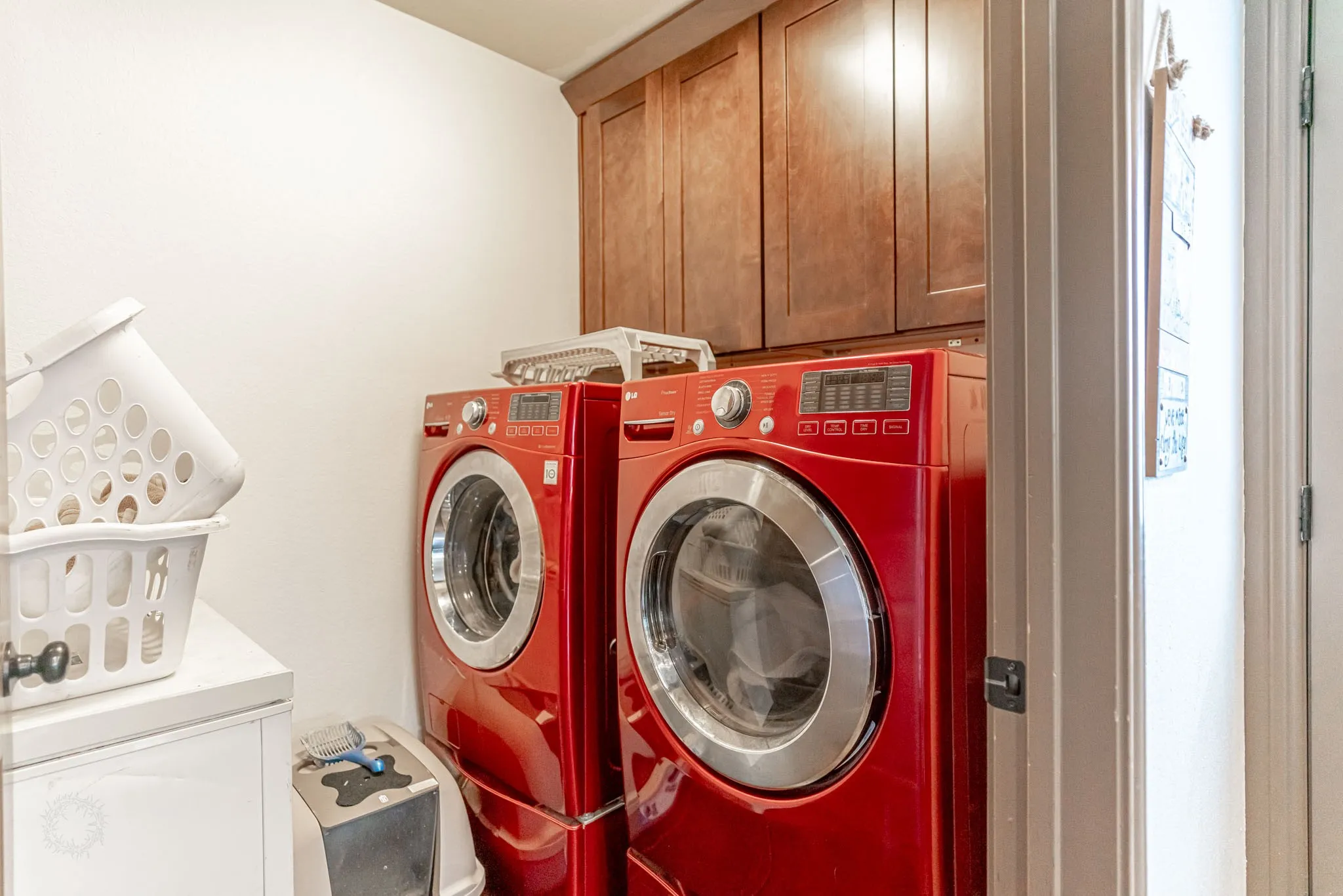 Dedicated laundry area featuring upper wood cabinetry and white walls