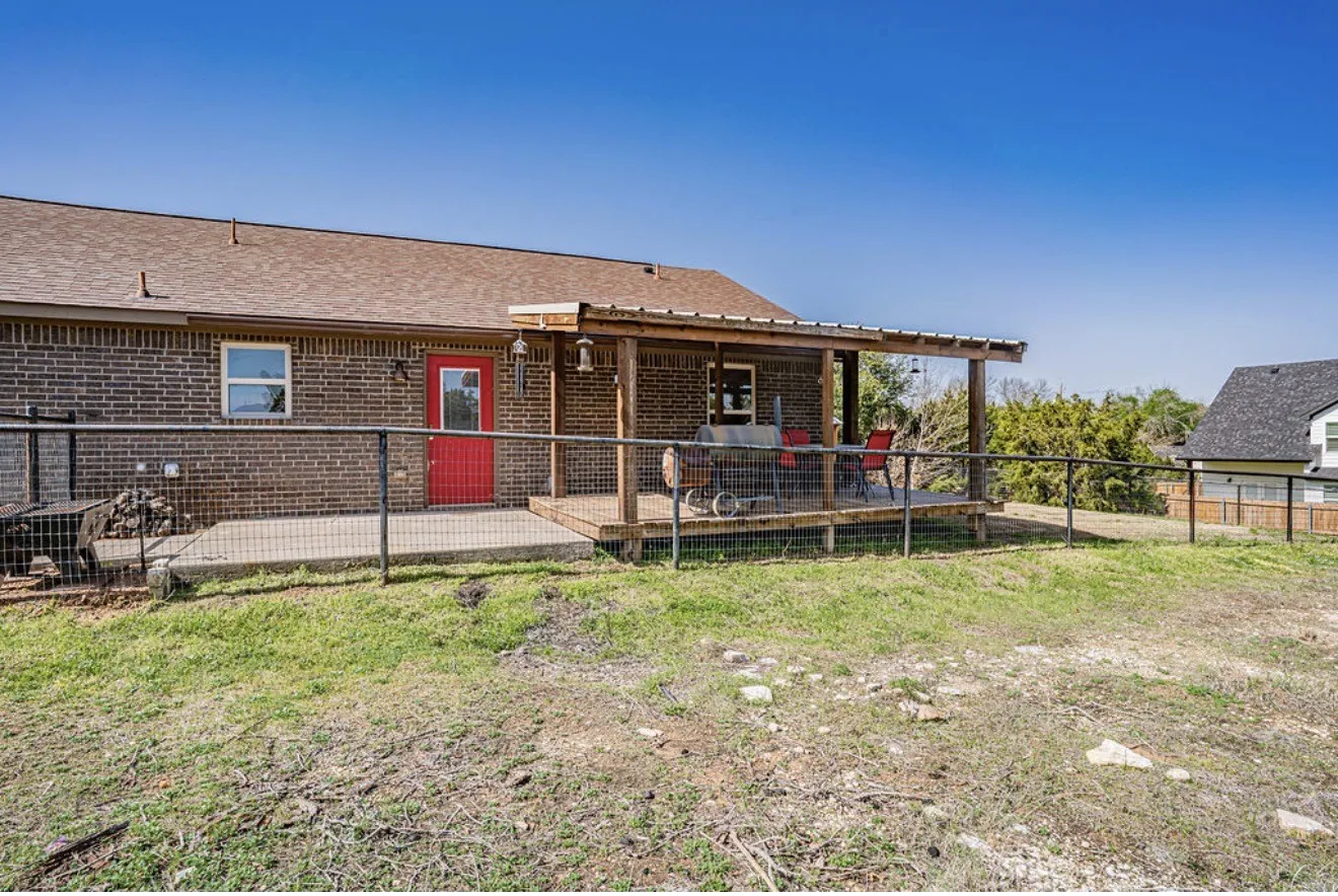 Expansive backyard featuring a covered patio, a wood deck with a metal roof, and a red exterior door