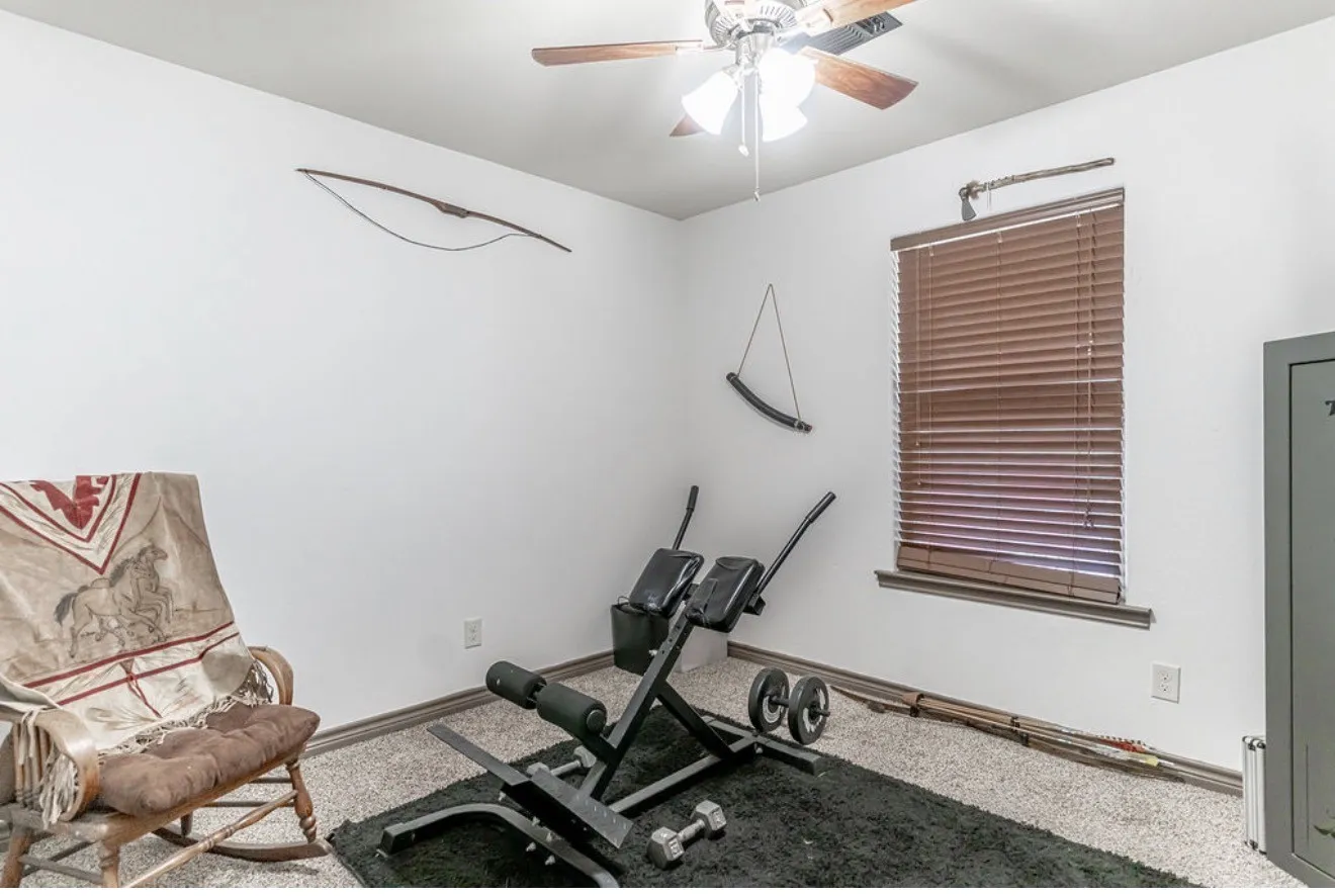 Room featuring light-colored textured carpet, a ceiling fan with integrated lighting, and a single window dressed with horizontal blinds