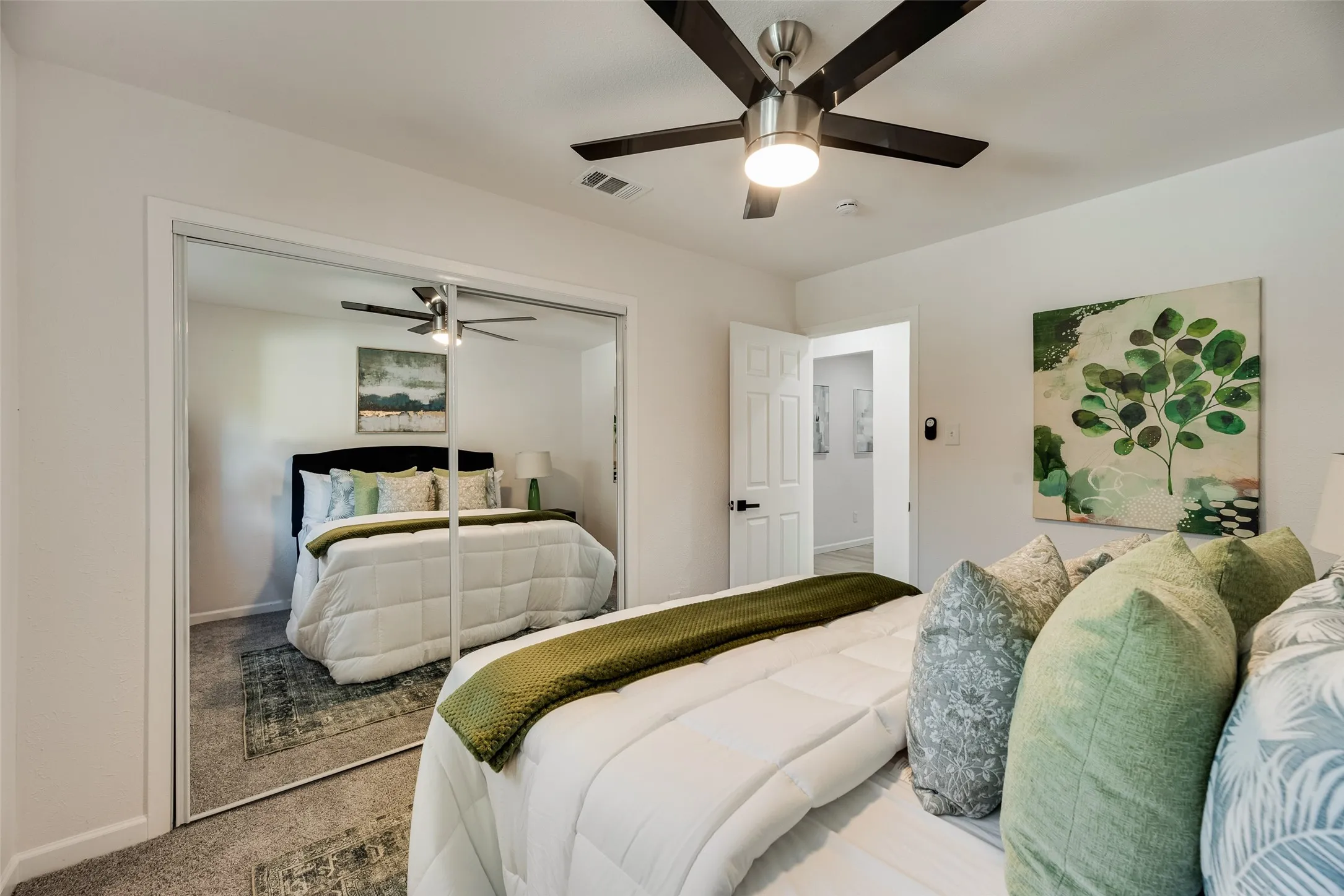 Bedroom featuring a ceiling fan with light, mirrored closet doors, and carpeted flooring