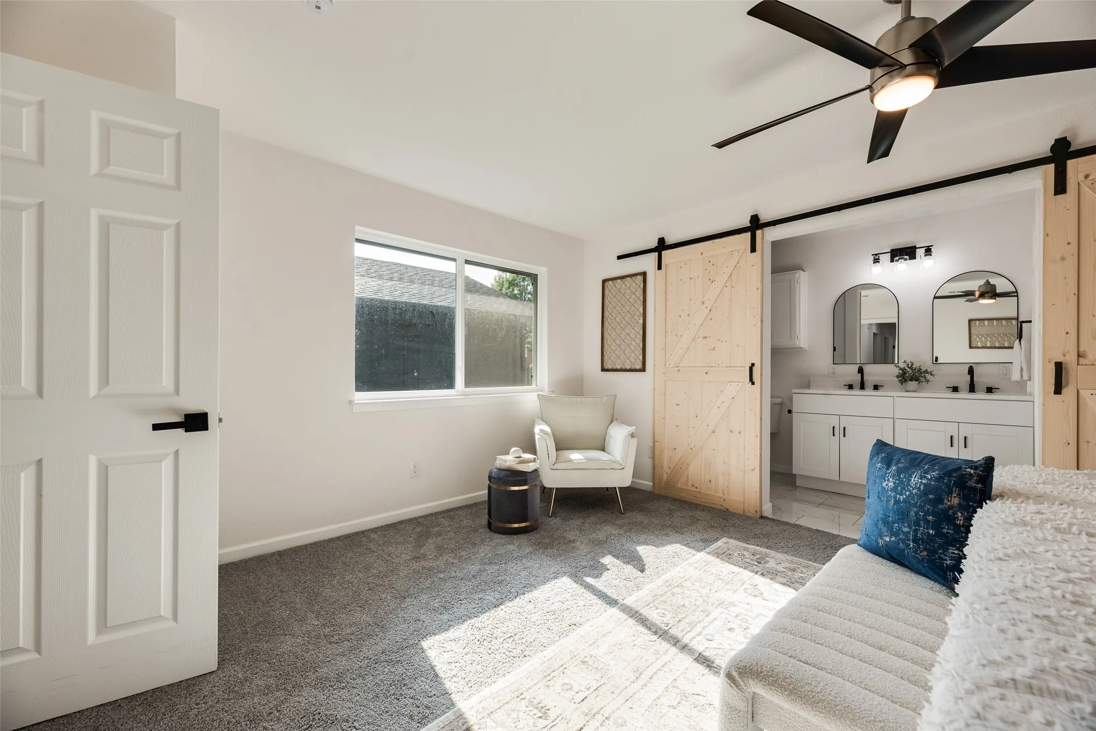 Bright interior space featuring light gray carpeting and a ceiling fan with integrated lighting