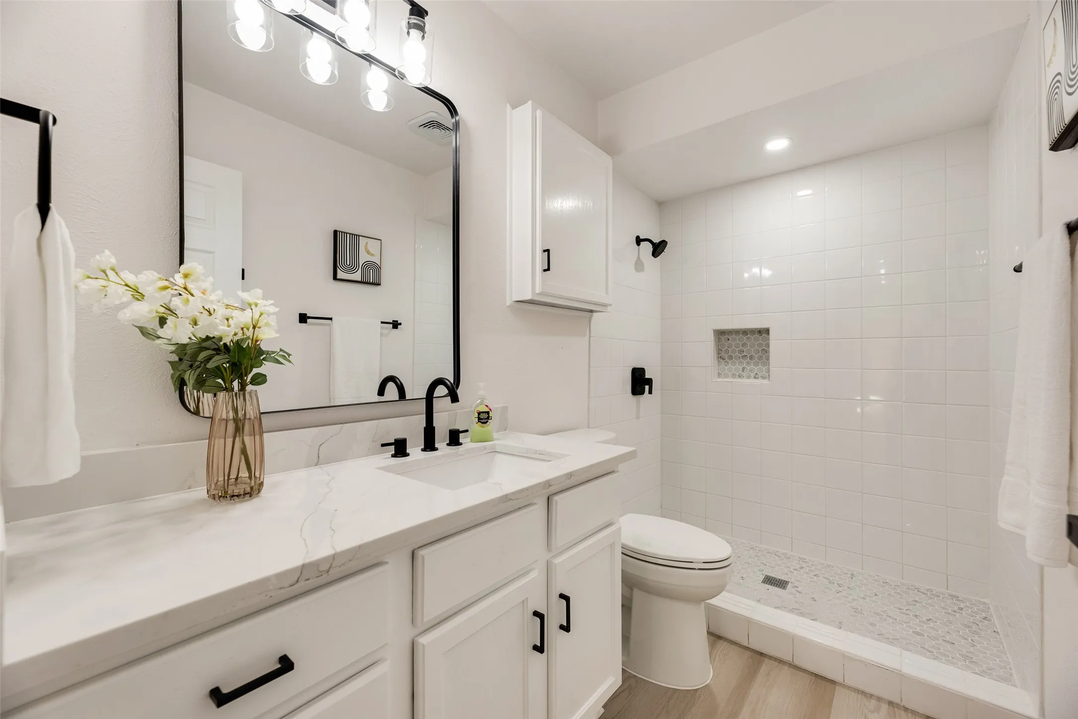 Bathroom featuring a single vanity with stone-finish countertop, undermount sink, and matte black fixtures