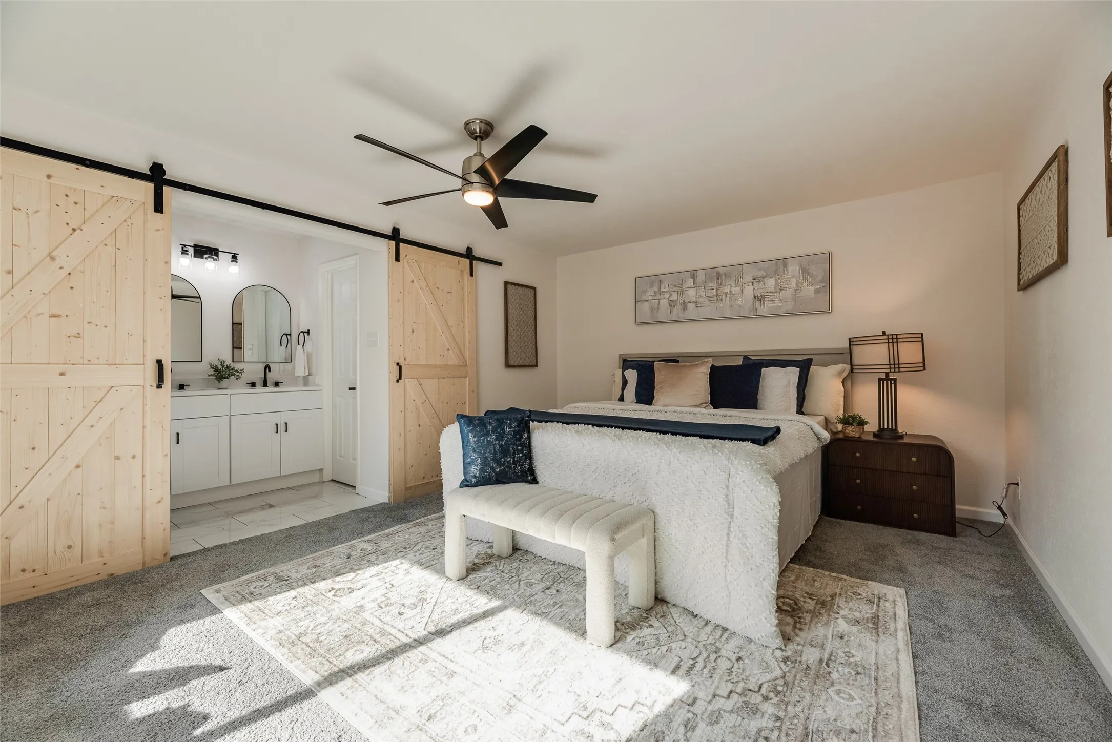 Carpeted room featuring a ceiling fan and barn door entry to a bathroom