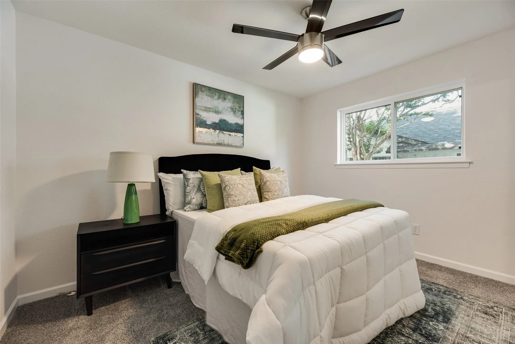 Bedroom featuring light grey carpeting, white walls, a single-pane window, and a ceiling fan with integrated lighting