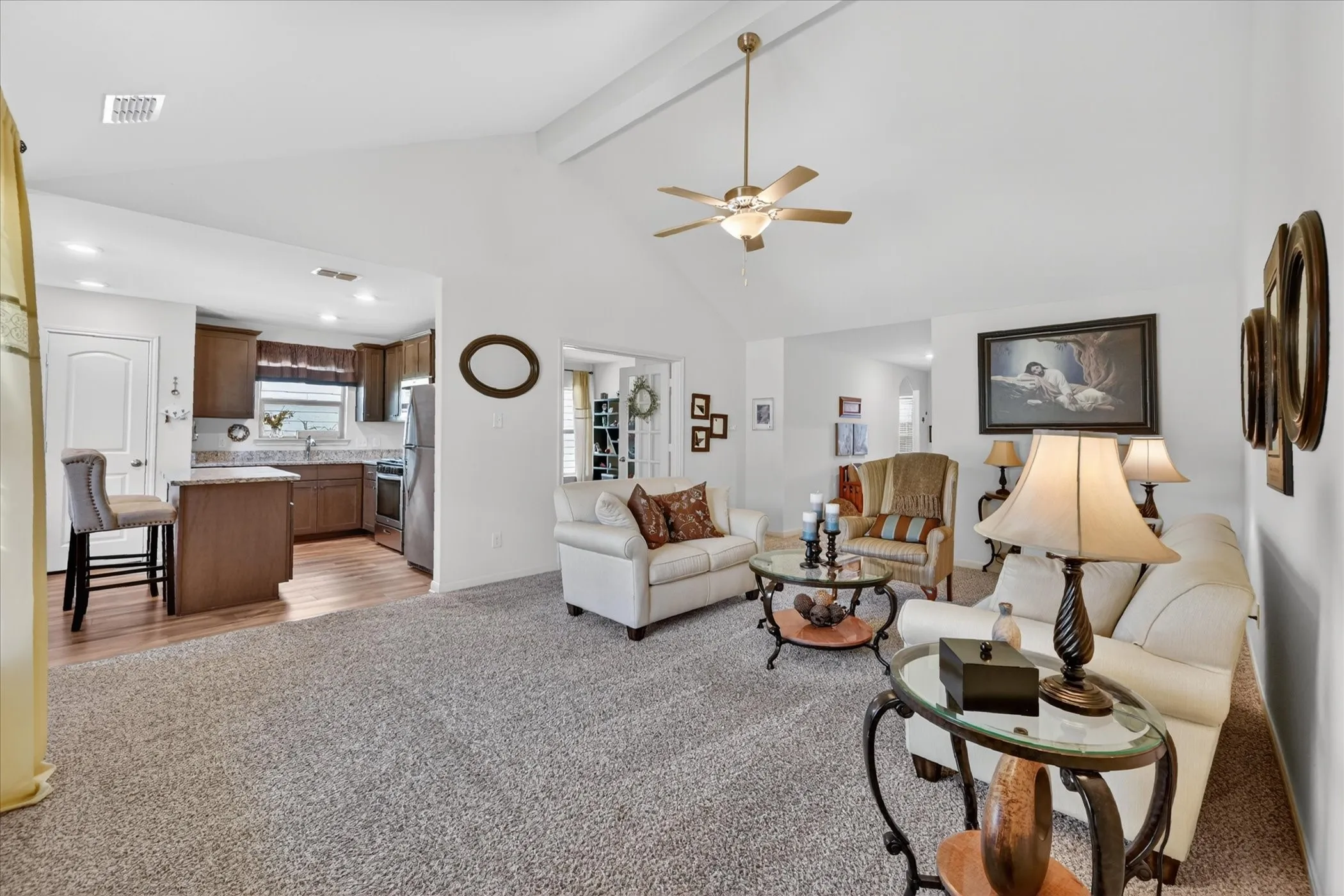 Spacious living area featuring a vaulted ceiling and ceiling fan