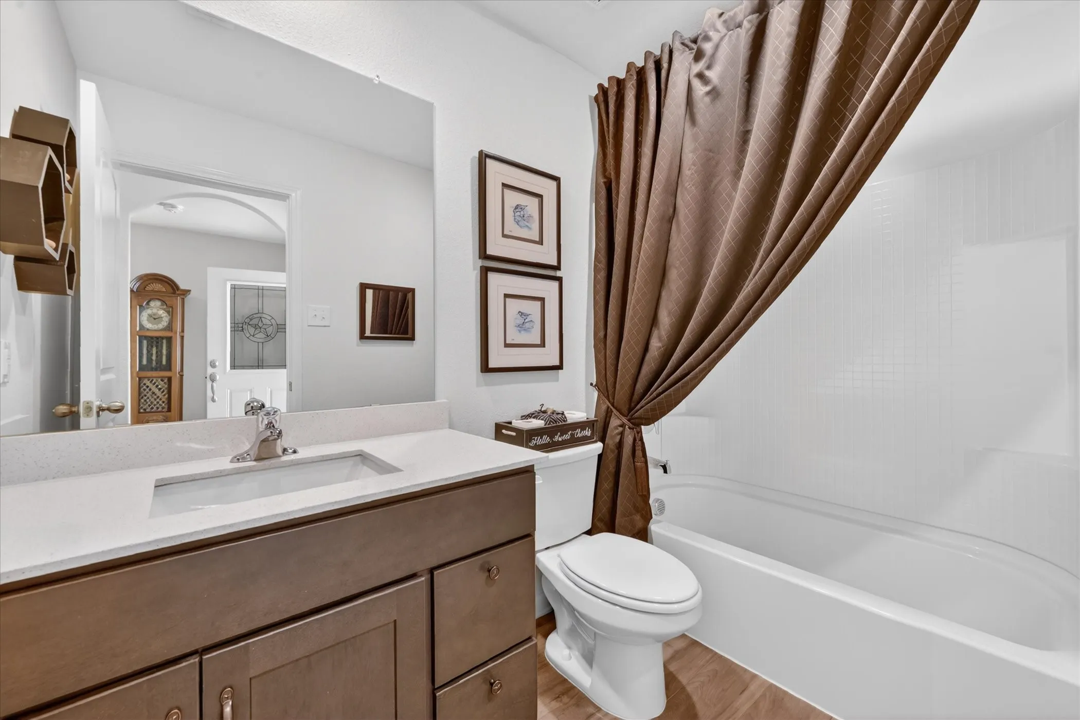 Bathroom featuring a wood-finish vanity with a light-toned countertop and an integrated rectangular sink