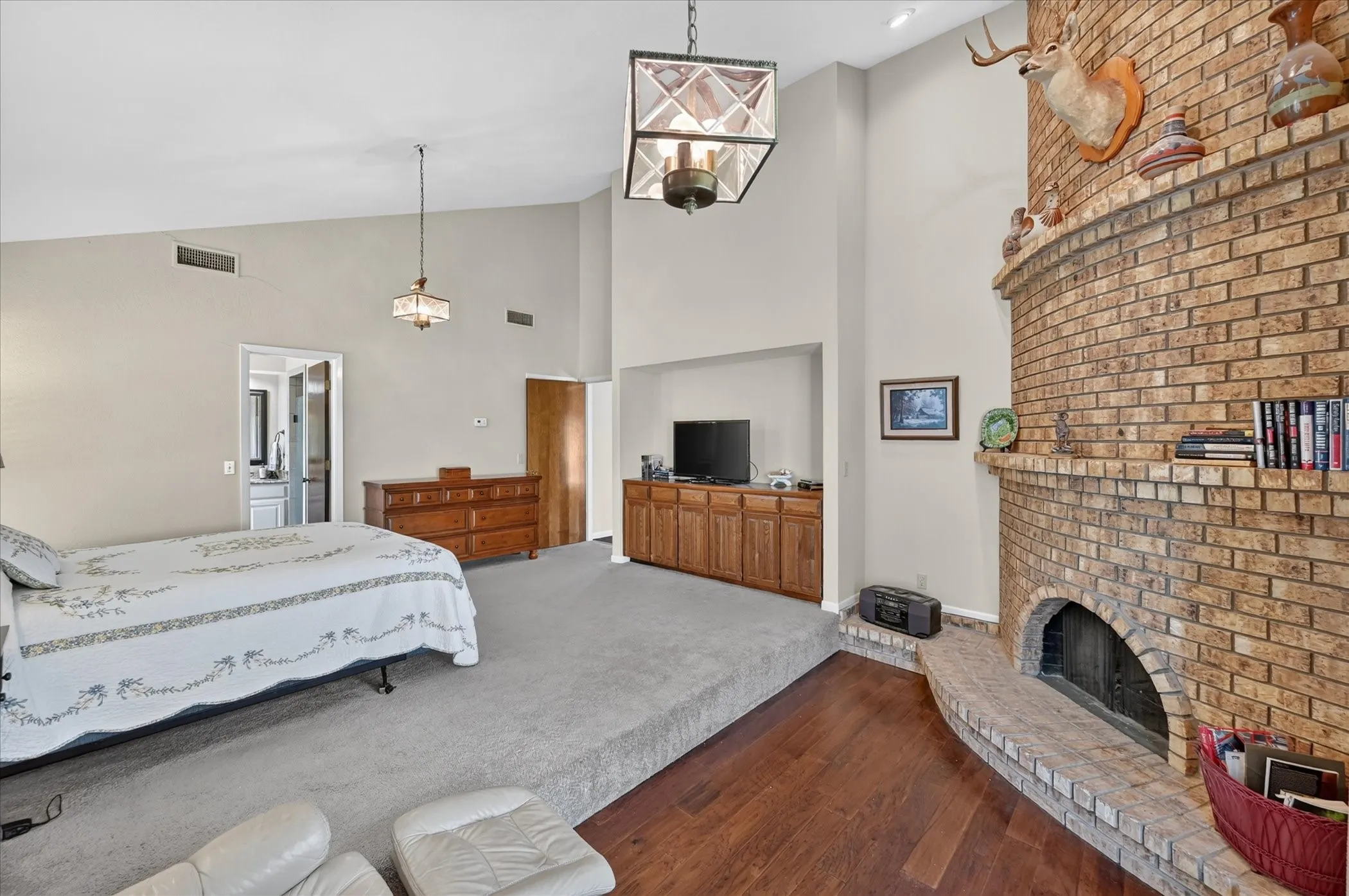 Primary bedroom, with corner fireplace, built in cabinets storage, walk in closet, vaulted ceilings, sitting area with wood floors!   Fabulous lighting!