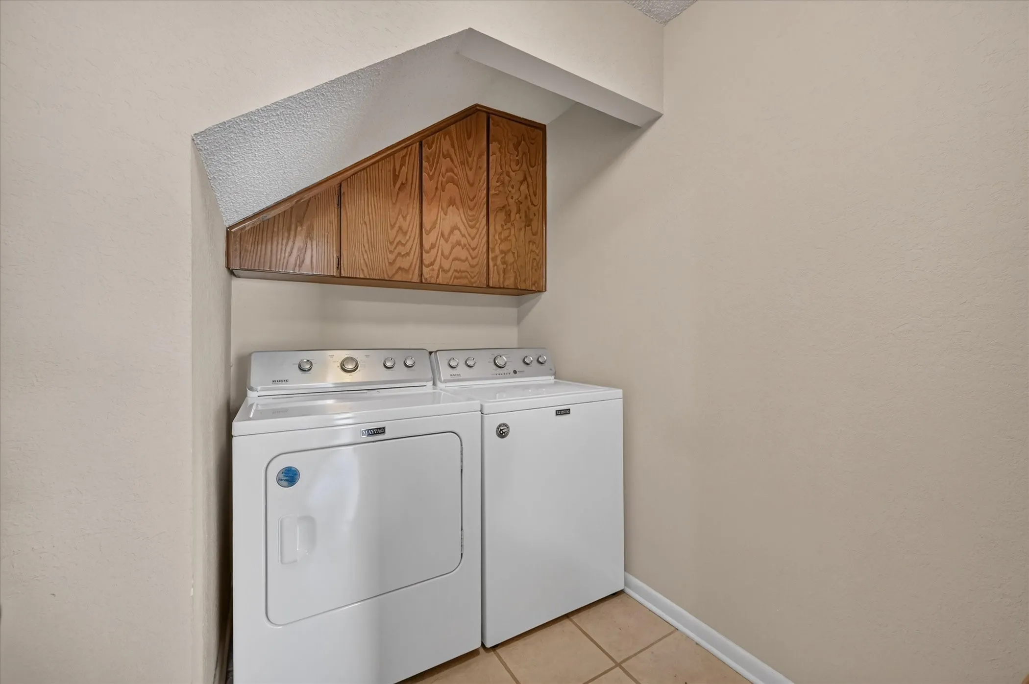 Separate laundry room with storage cabinets & tile floors!