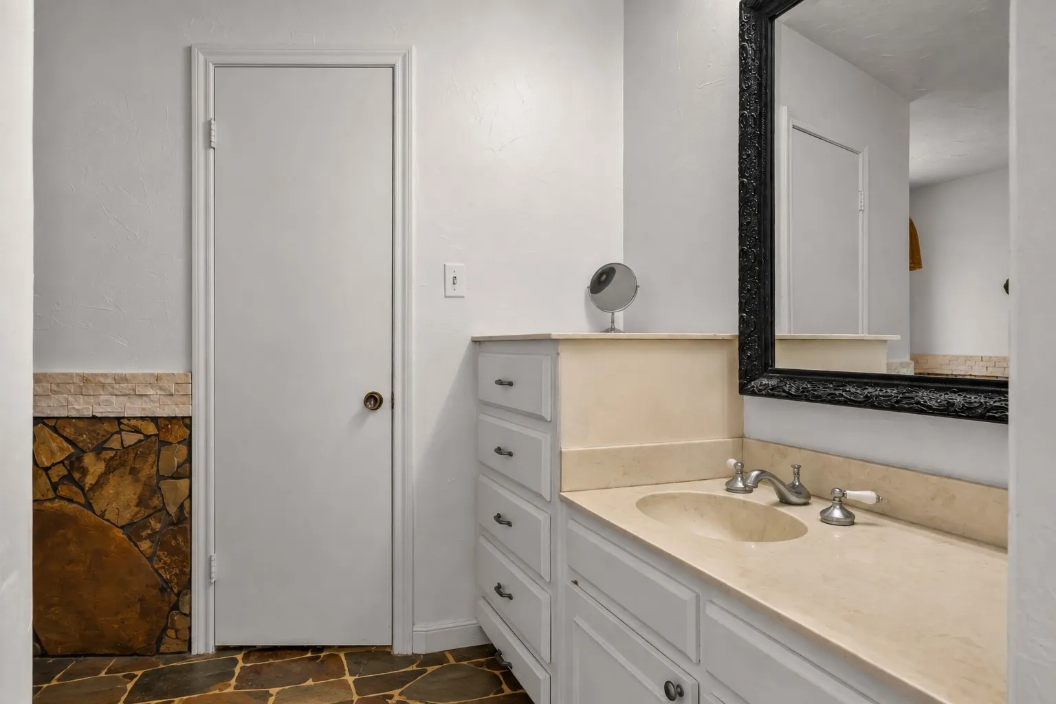 Built-in vanity with light-toned countertop and integrated sink, white cabinetry with multiple drawers, and a framed mirror