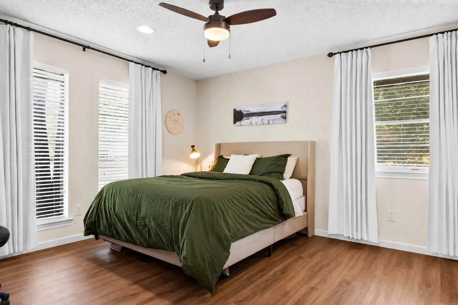 Wood-finish flooring with recessed lighting, multiple windows, and a ceiling fan