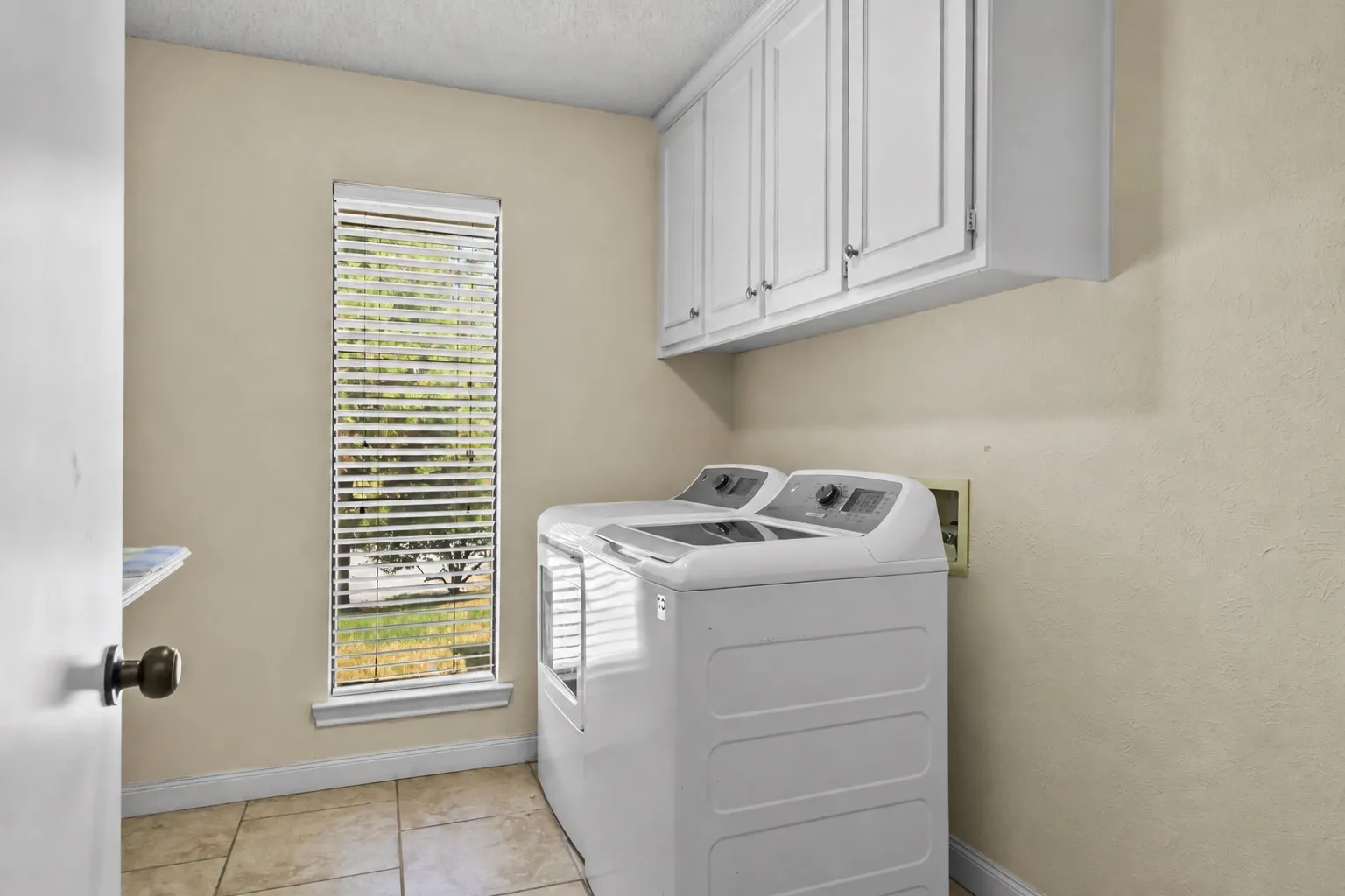 Built-in upper cabinetry, tiled flooring, natural light window with blinds, and durable wall finish
