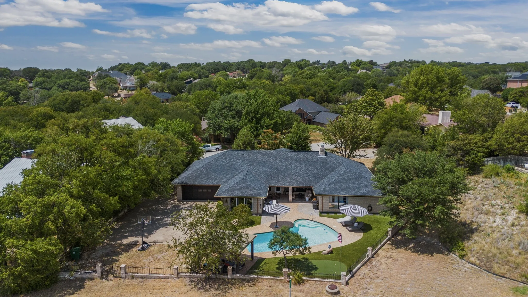 Ranch-style residence featuring a dark shingle roof, attached garage, and a rear-facing covered patio