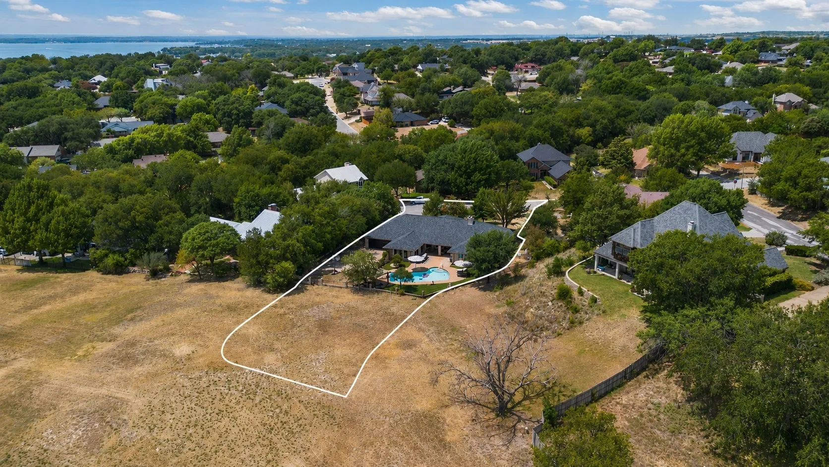 Aerial perspective showcasing a property with mature trees, a swimming pool, and a large undeveloped parcel that is included in this property as a seperate parcel