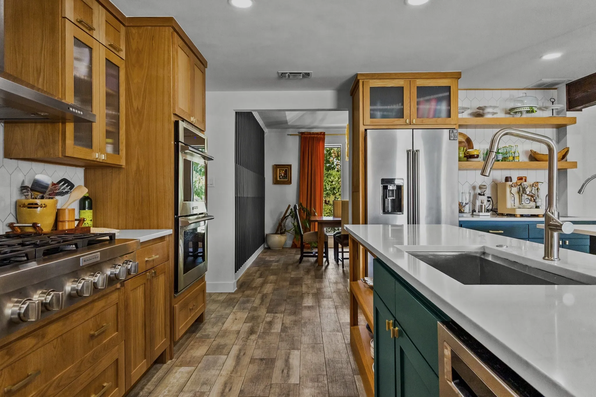 Gourmet kitchen with wood-finish flooring, stainless steel appliances, white countertops, and a subway tile backsplash