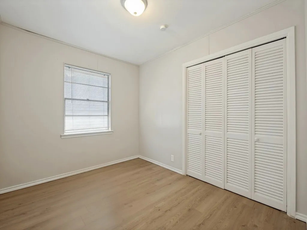 Bright bedroom offering vinyl plank flooring, a large window, and cedar lined closet providing ample storage