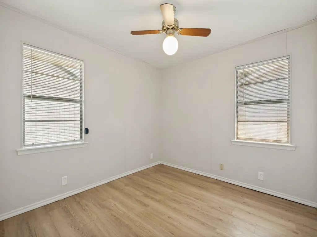 Bright corner bedroom with abundant natural light from dual windows, vinyl plank flooring throughout, ceiling fan and cedar lined closet