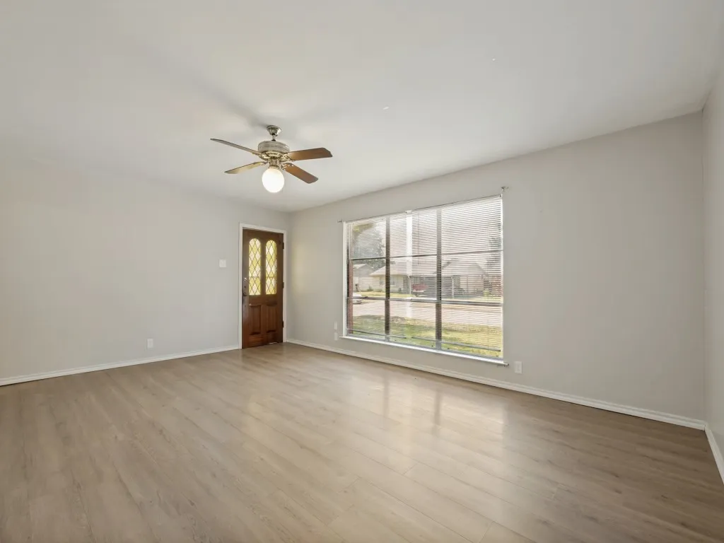 Oversized living area with vinyl plank flooring and natural light through large front window