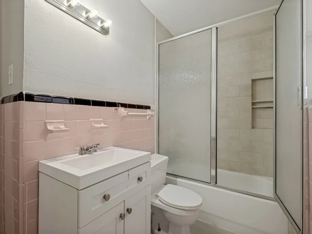 Clean and functional bathroom featuring a white vanity with storage drawers, chrome faucet fixtures, and bathtub shower