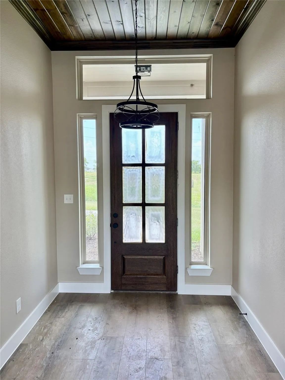 Entryway featuring a dark wood-finish plank door with glass panels, flanked by two vertical windows