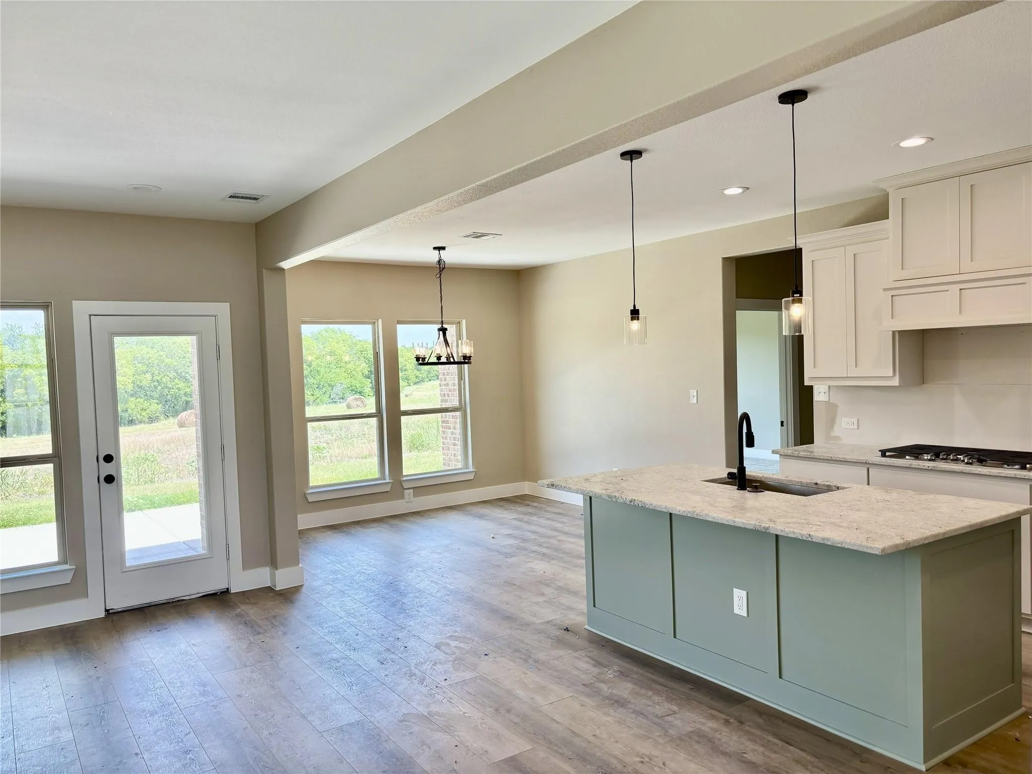 Open-concept living space featuring wood-finish flooring, a kitchen island with stone countertops, and white cabinetry