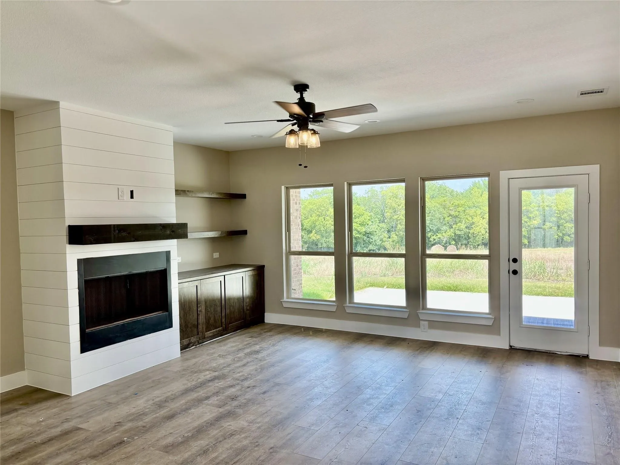 Spacious interior featuring wood-finish flooring, a contemporary fireplace with a dark wood mantel, and built-in shelving with cabinetry