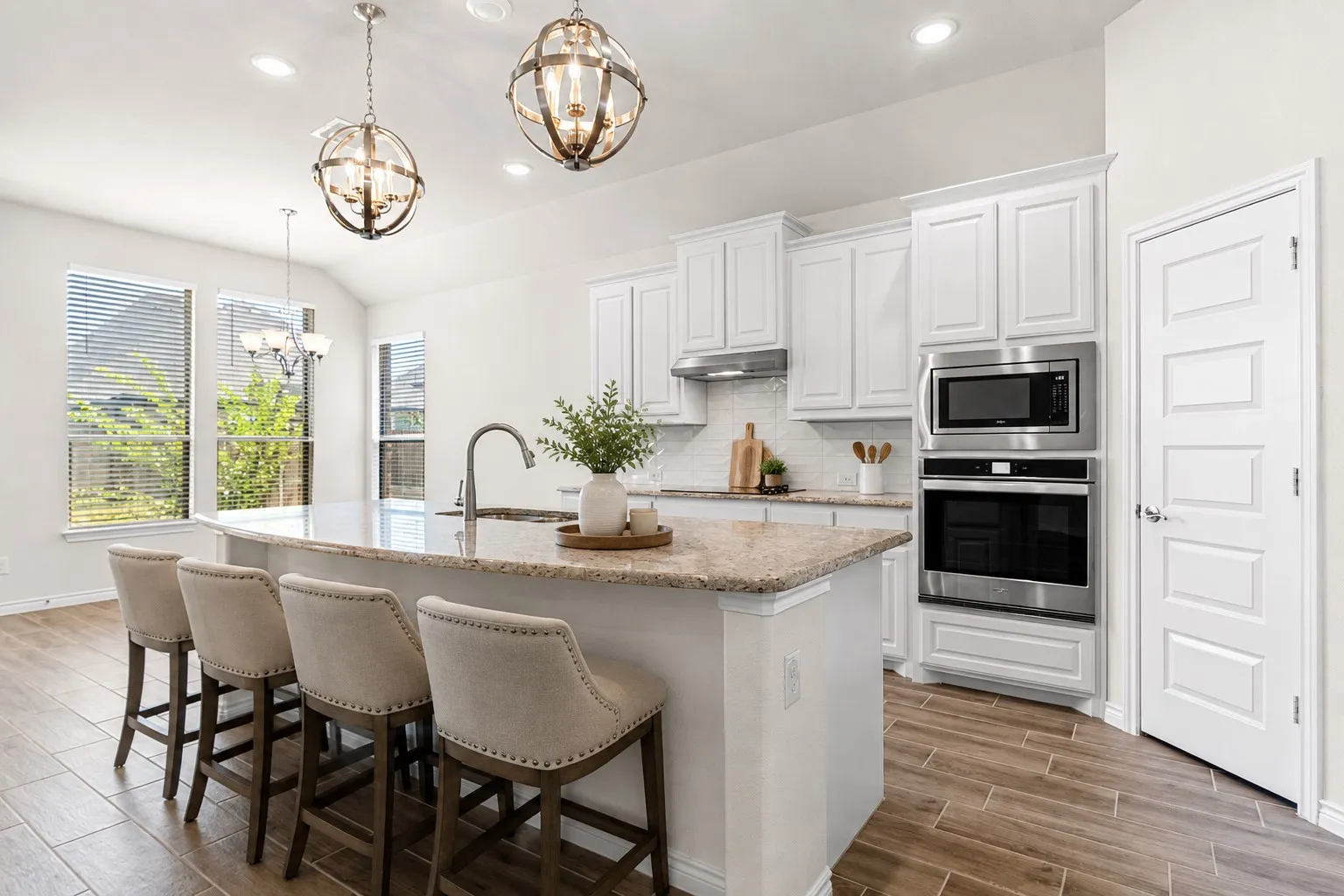 Kitchen featuring a large curved island with a stone countertop, white shaker-style cabinetry, stainless steel built-in appliances, and wood-finish tile flooring