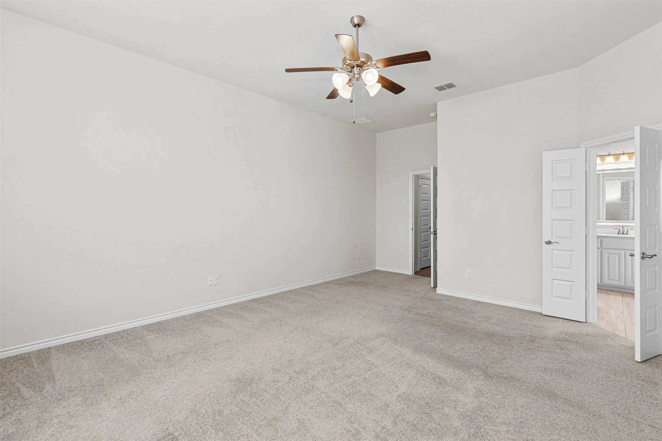 Spacious room featuring light-colored carpeting, high ceilings, and a ceiling fan with integrated lighting