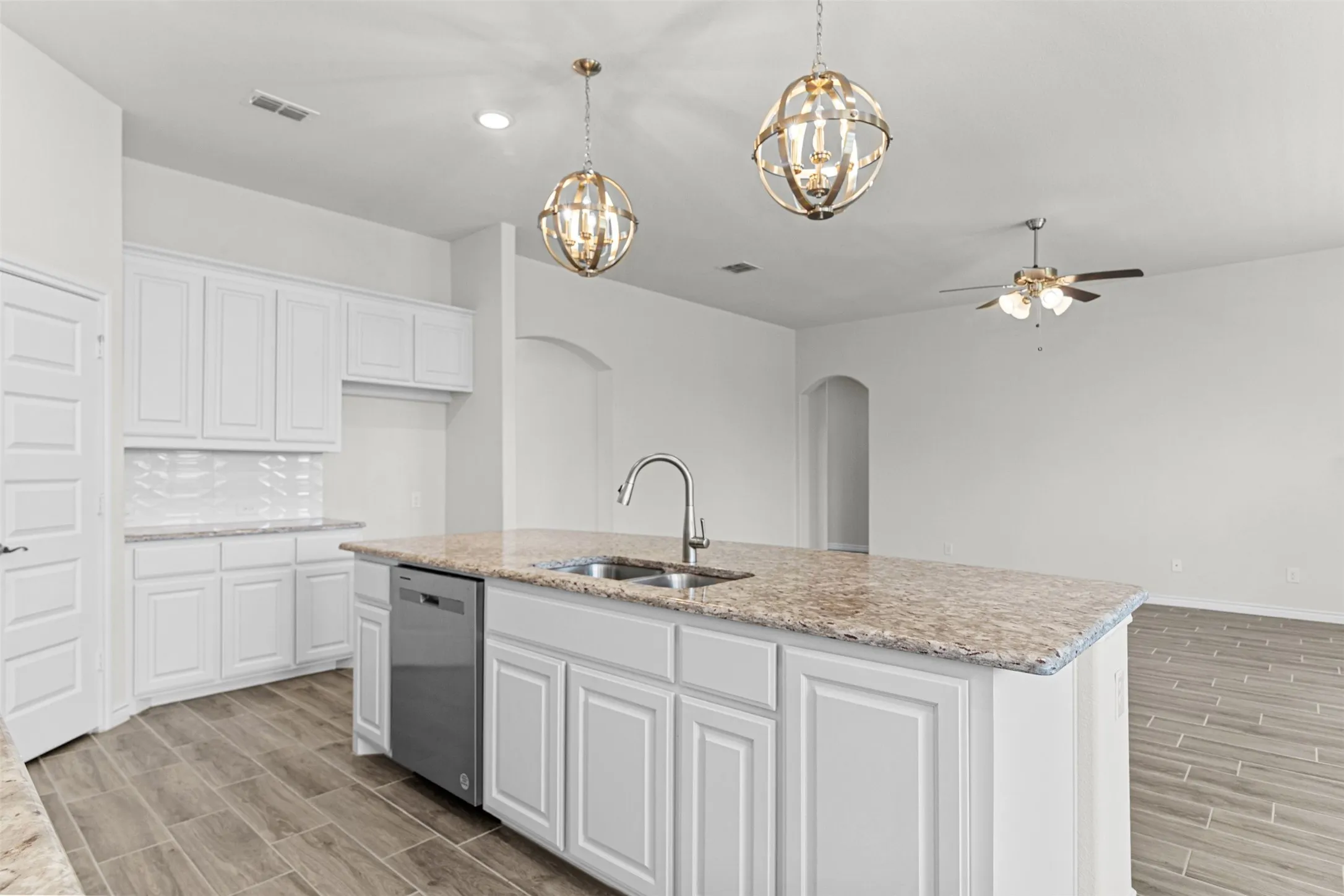 Kitchen island with a double basin sink, stainless steel faucet, and granite-style countertop