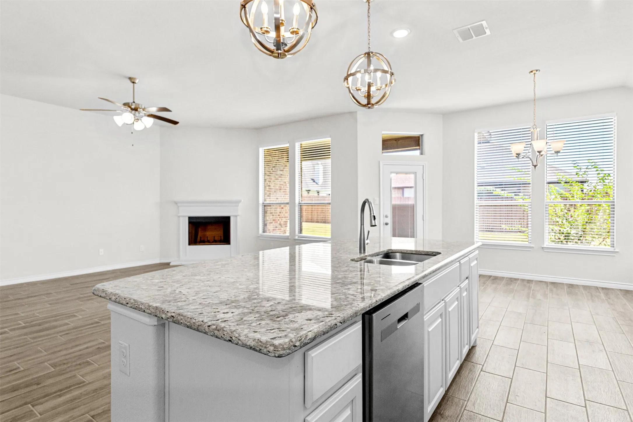 Spacious kitchen island featuring a granite countertop, integrated sink with gooseneck faucet, and stainless steel dishwasher