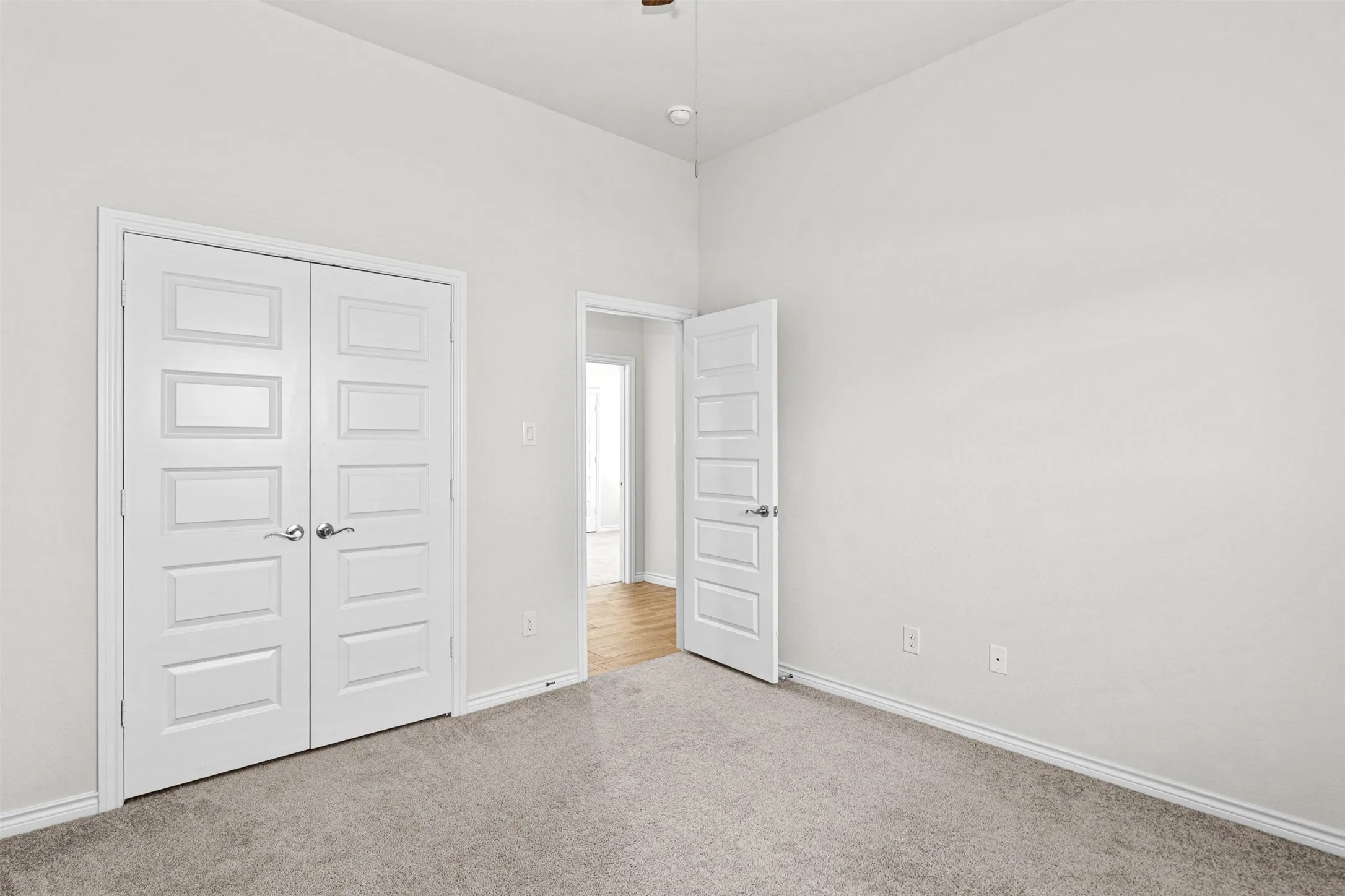 Spacious bedroom featuring neutral wall finishes, recessed ceiling lighting, and dual white panel doors with multiple horizontal panels