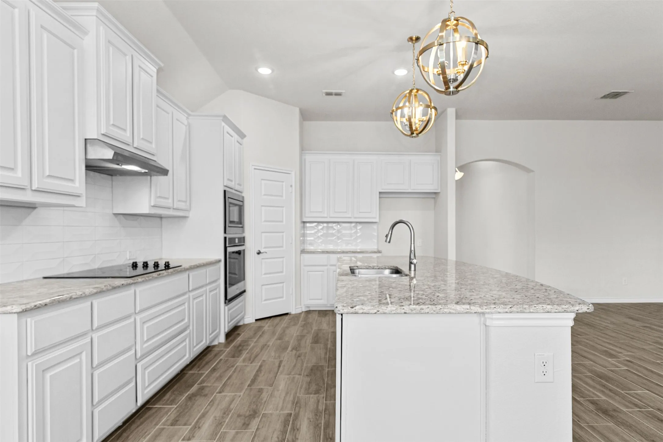 Bright kitchen featuring white cabinetry, light-colored countertops, a built-in oven, a built-in microwave, and wood-finish flooring