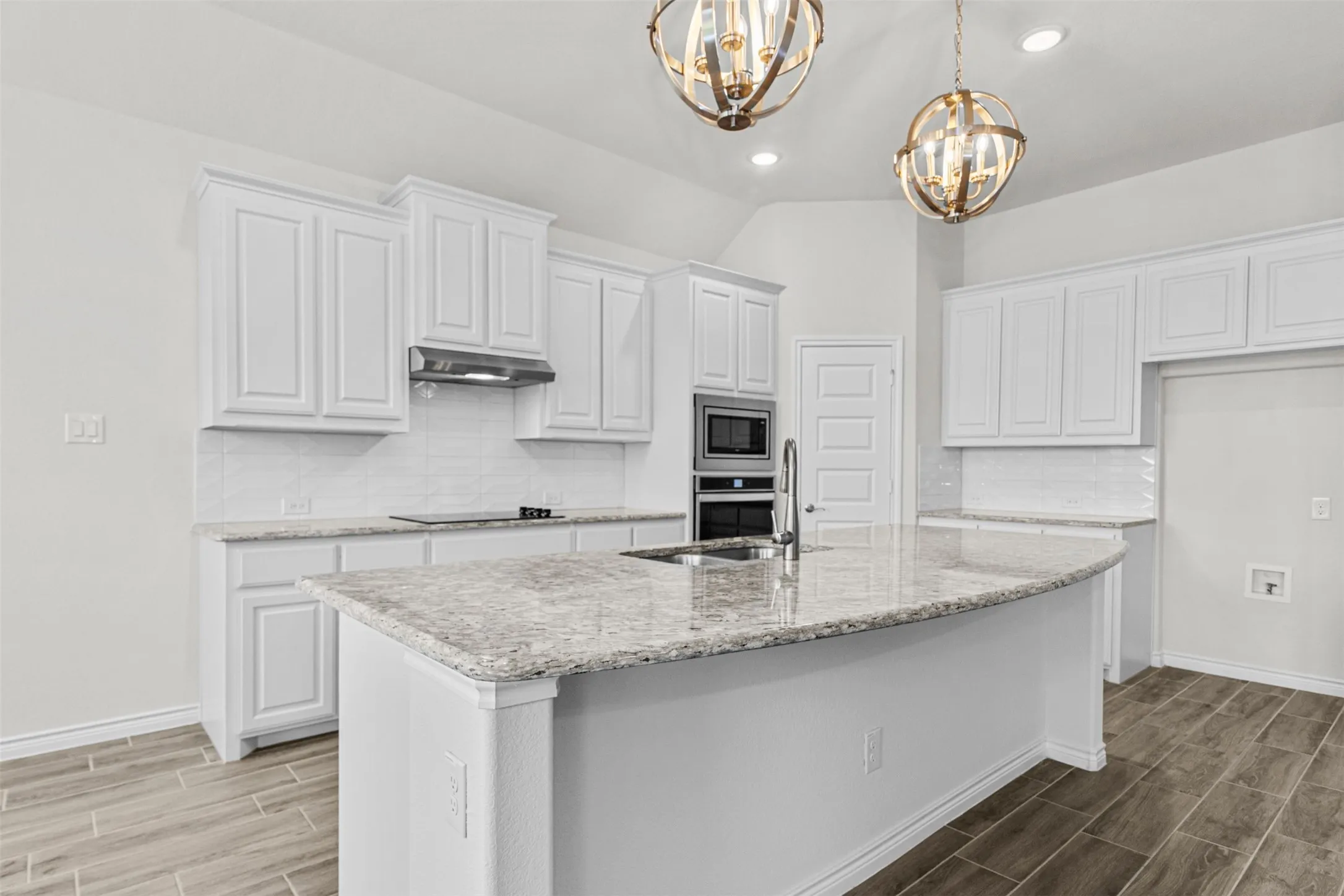 Modern kitchen featuring white cabinetry, stone countertops, a subway tile backsplash, and wood-finish flooring