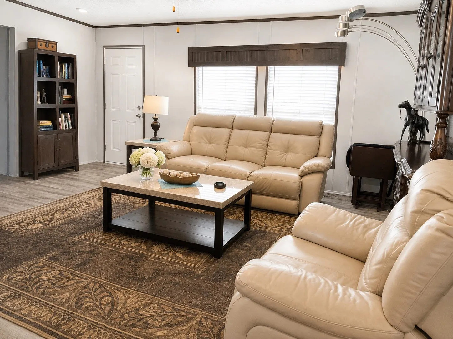Spacious living area featuring wood-finish flooring, white paneling, and dark wood trim