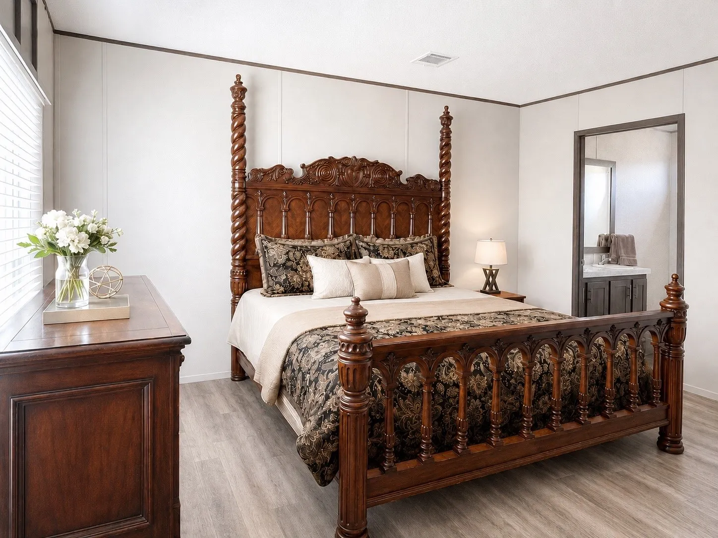 Spacious room featuring light wood-finish flooring, white wall panels, and a large window with blinds