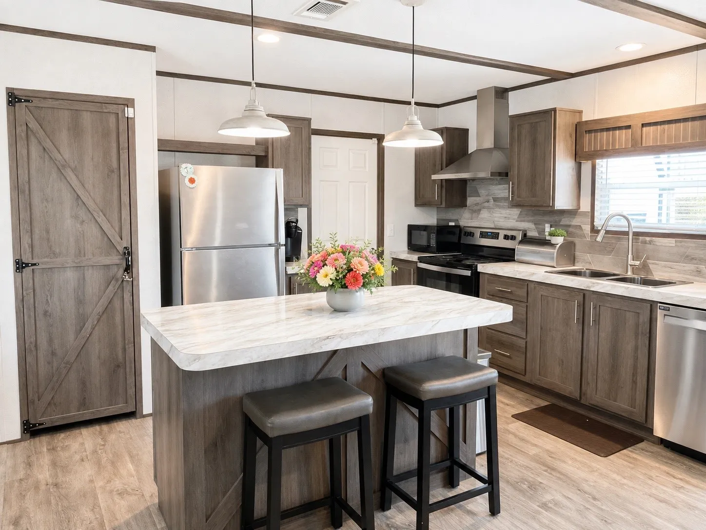 Kitchen featuring an island with seating, stainless steel appliances, wood-finish flooring, recessed lighting, and a barn-style pantry door