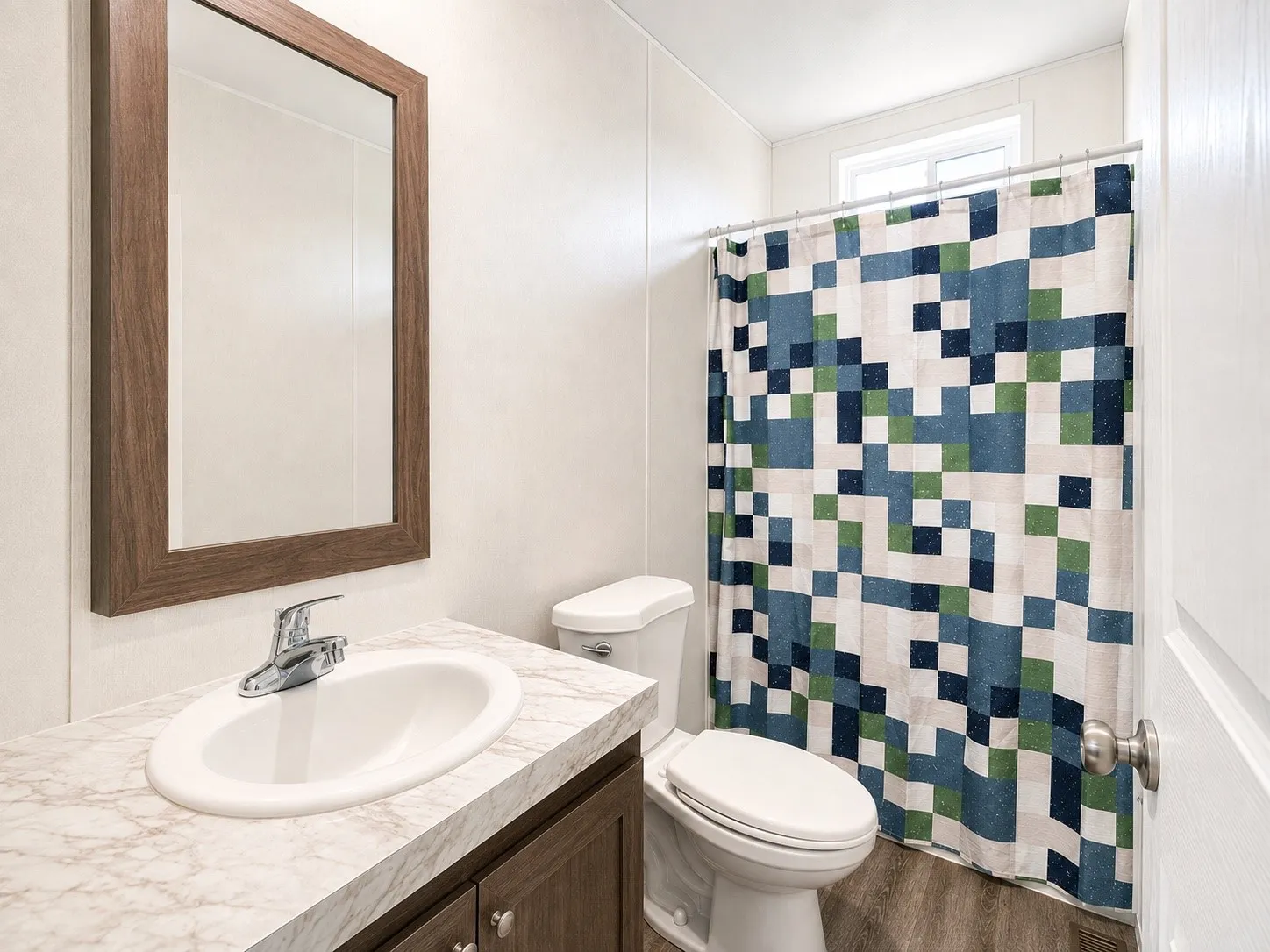 Bathroom vanity featuring a wood-finish framed mirror, a countertop with a subtle veining pattern, and an undermount sink with a chrome faucet