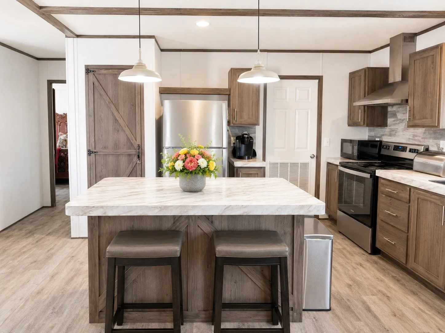 Open-concept kitchen featuring an island with a white marble-look countertop and two pendant light fixtures