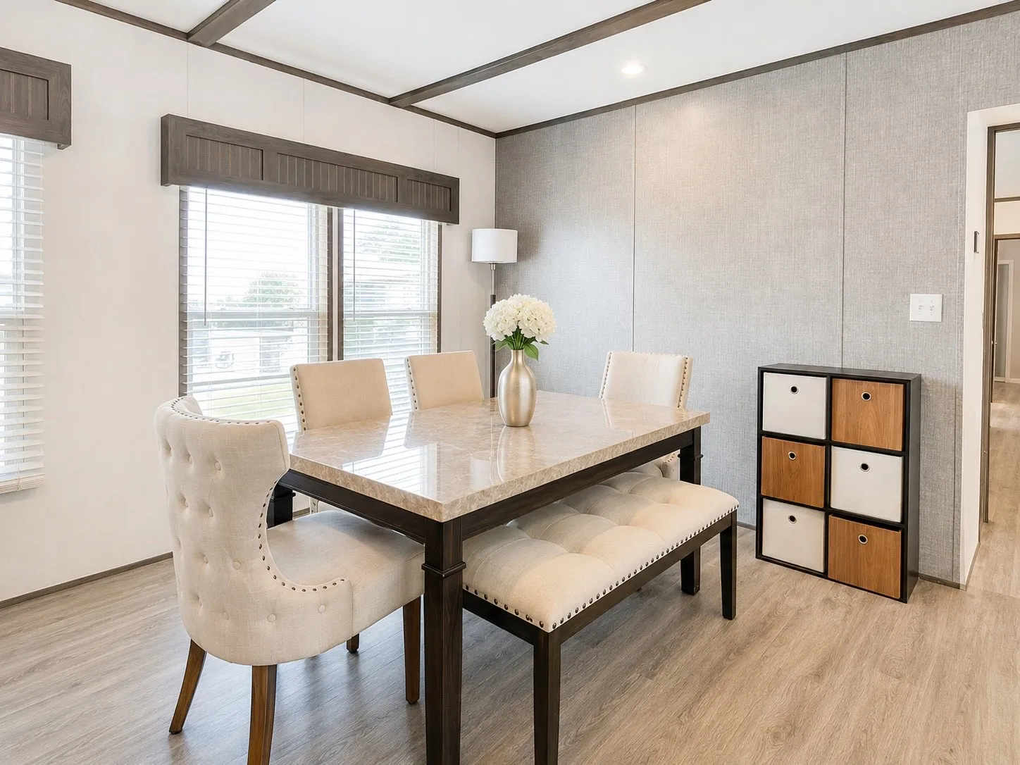 Dining area featuring wood-finish flooring, accent wall paneling, and a window with blinds and dark wood-finish valance