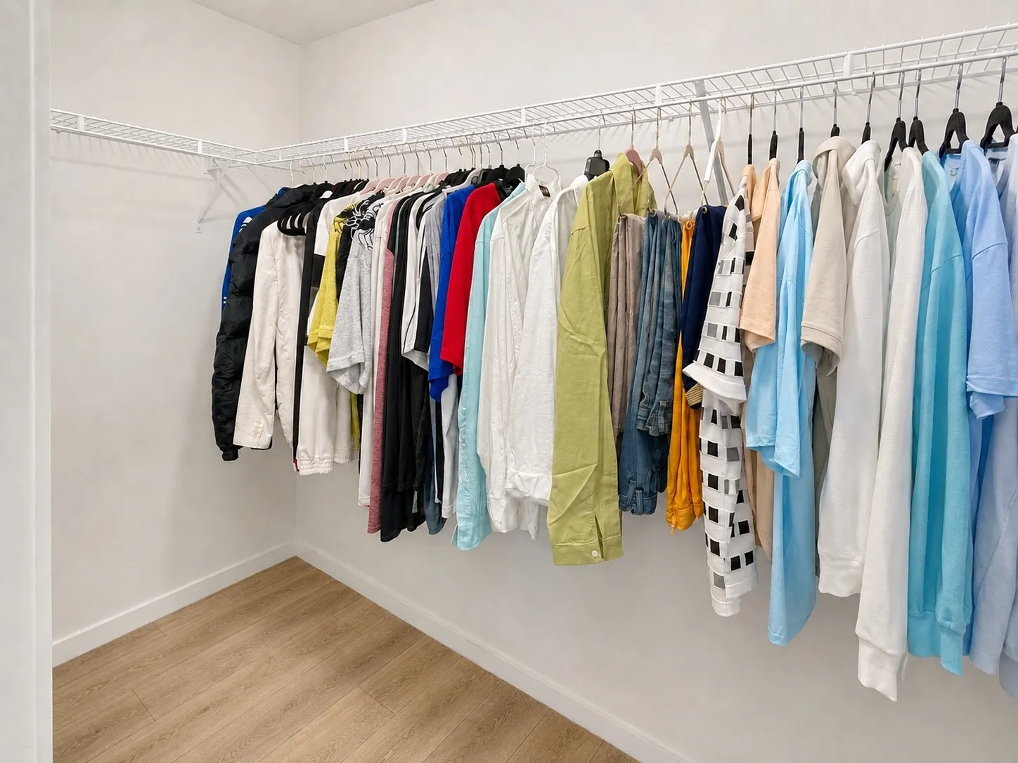 Walk-in closet featuring white wire shelving, ample hanging space, and wood-finish flooring