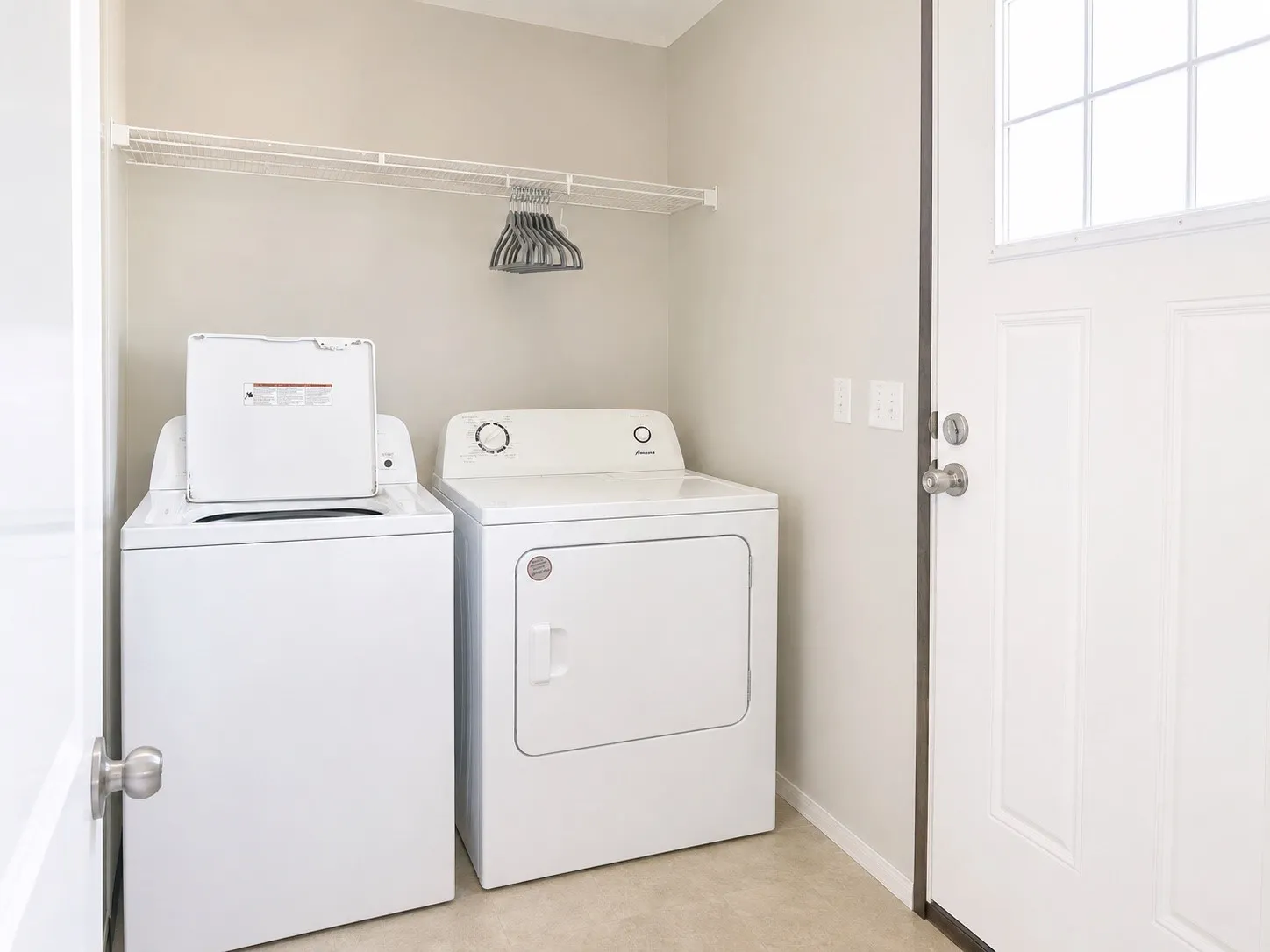 Dedicated laundry area featuring a top-load washing machine, front-load dryer, and overhead wire shelving