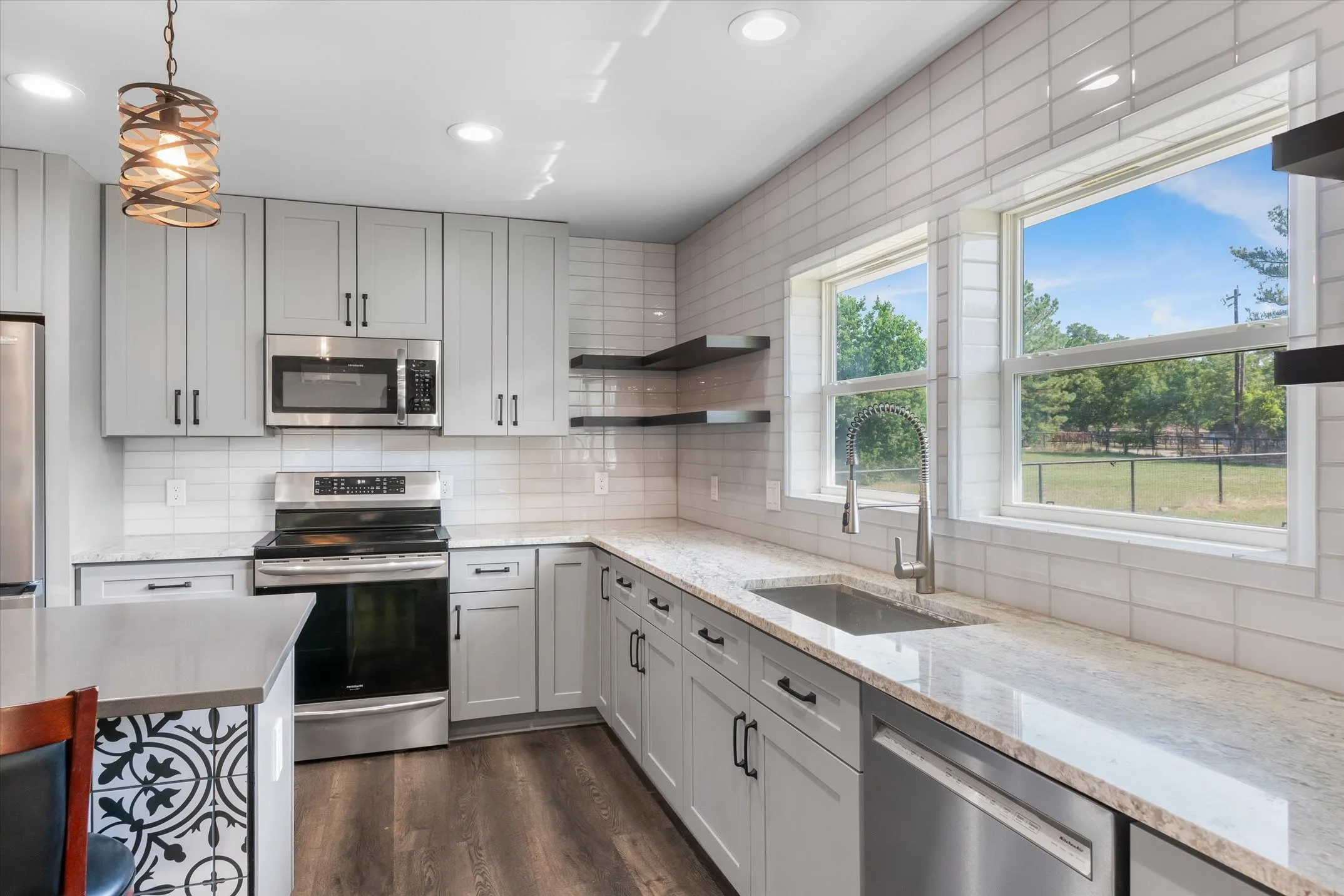 Modern kitchen featuring light gray cabinetry, stainless steel appliances, white subway tile backsplash, and light-toned countertops